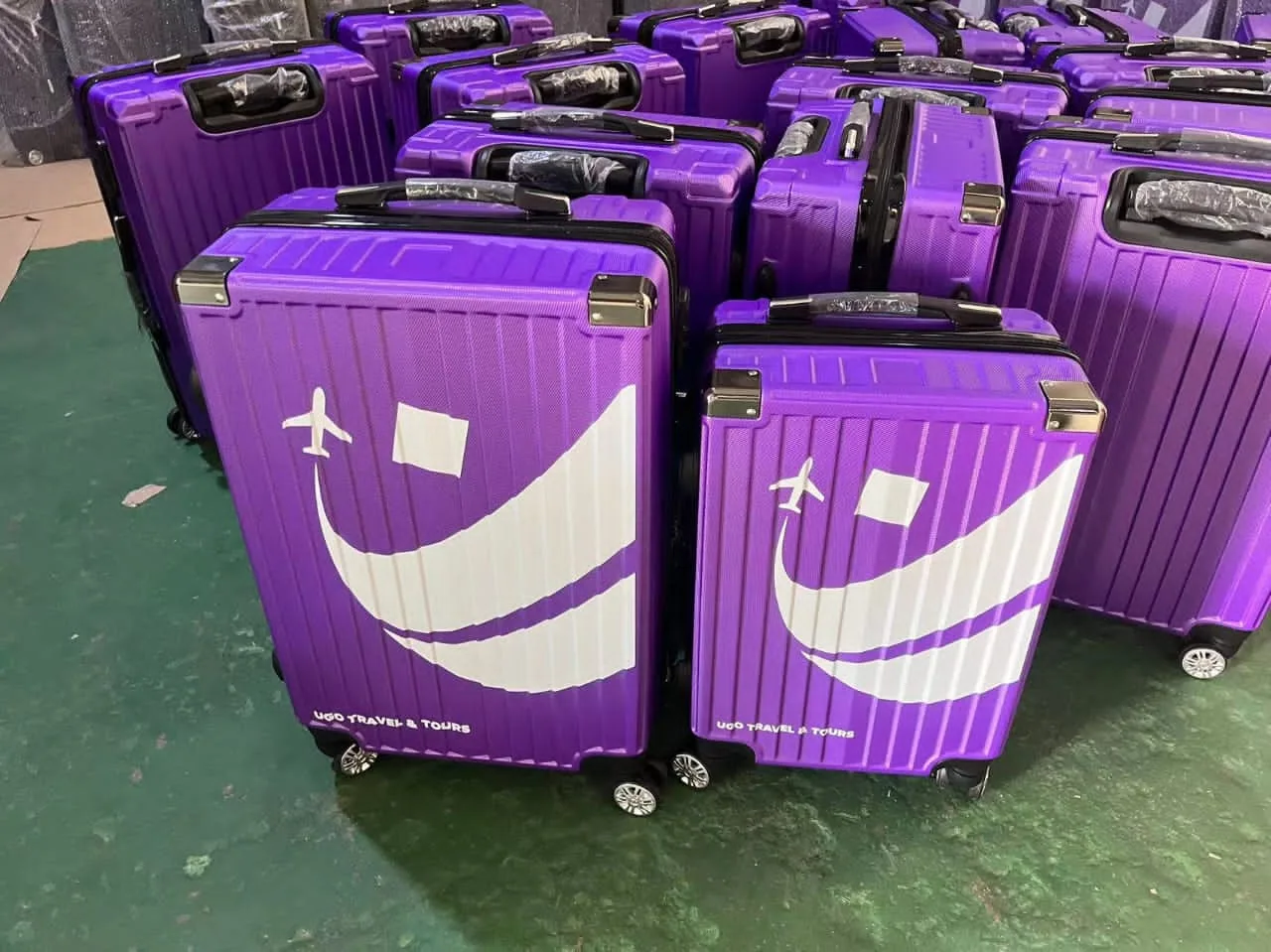 Rows of purple cases printed with a travel agency's smile logo, ready to ship