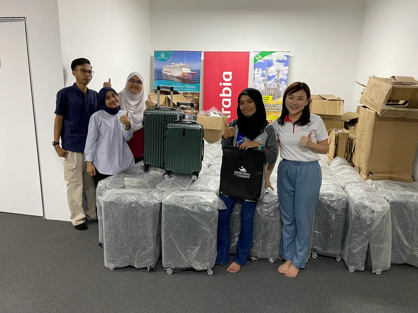 The Manazel Mashaer Travel team beside their wrapped stock of green cases