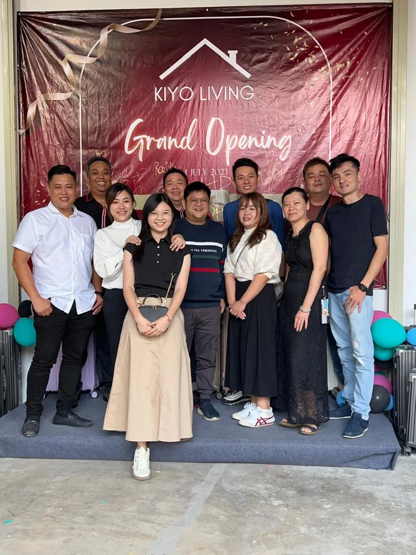 Guests with a child in front of the KIYO Living grand opening backdrop, cases beside them