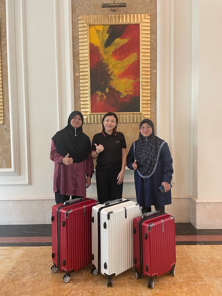 Three women in a lobby with three sample cases, two red and one silver